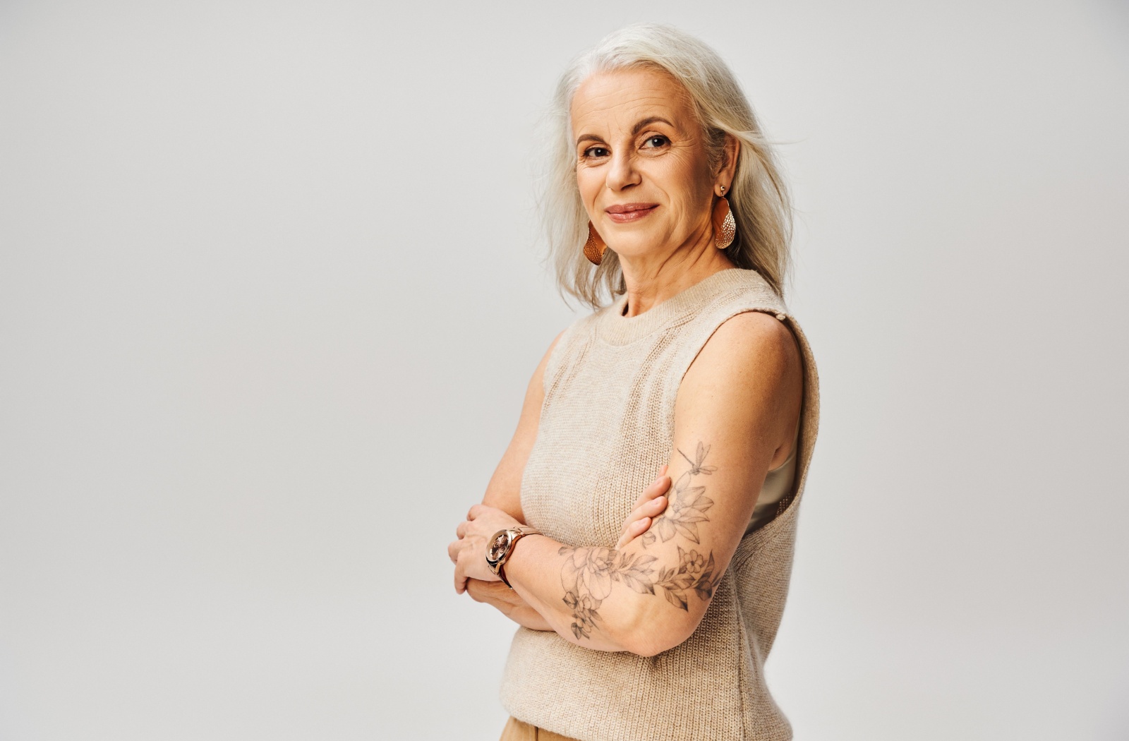 A senior smiles with their arms crossed, showing off a new tattoo.