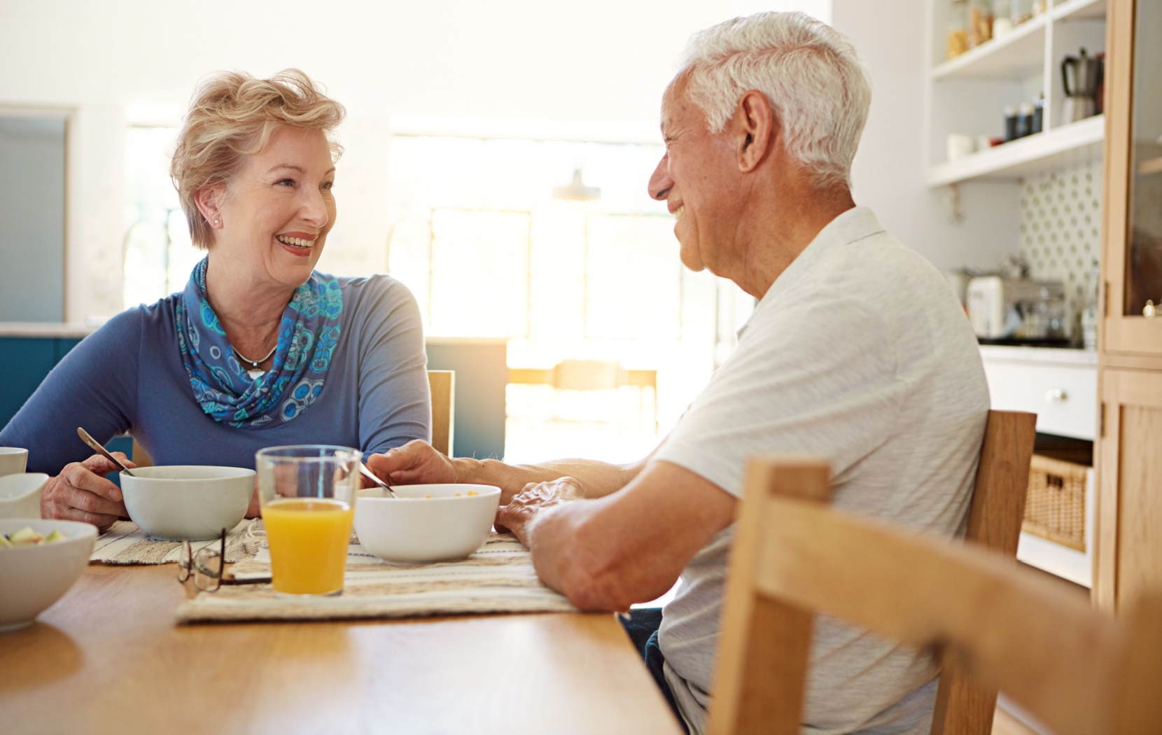 Two seniors enjoy breakfast together while smiling at each other