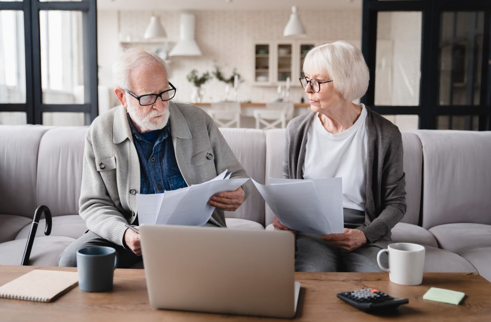 A senior couple looks through financial documents, exploring the cost of moving to independent living.