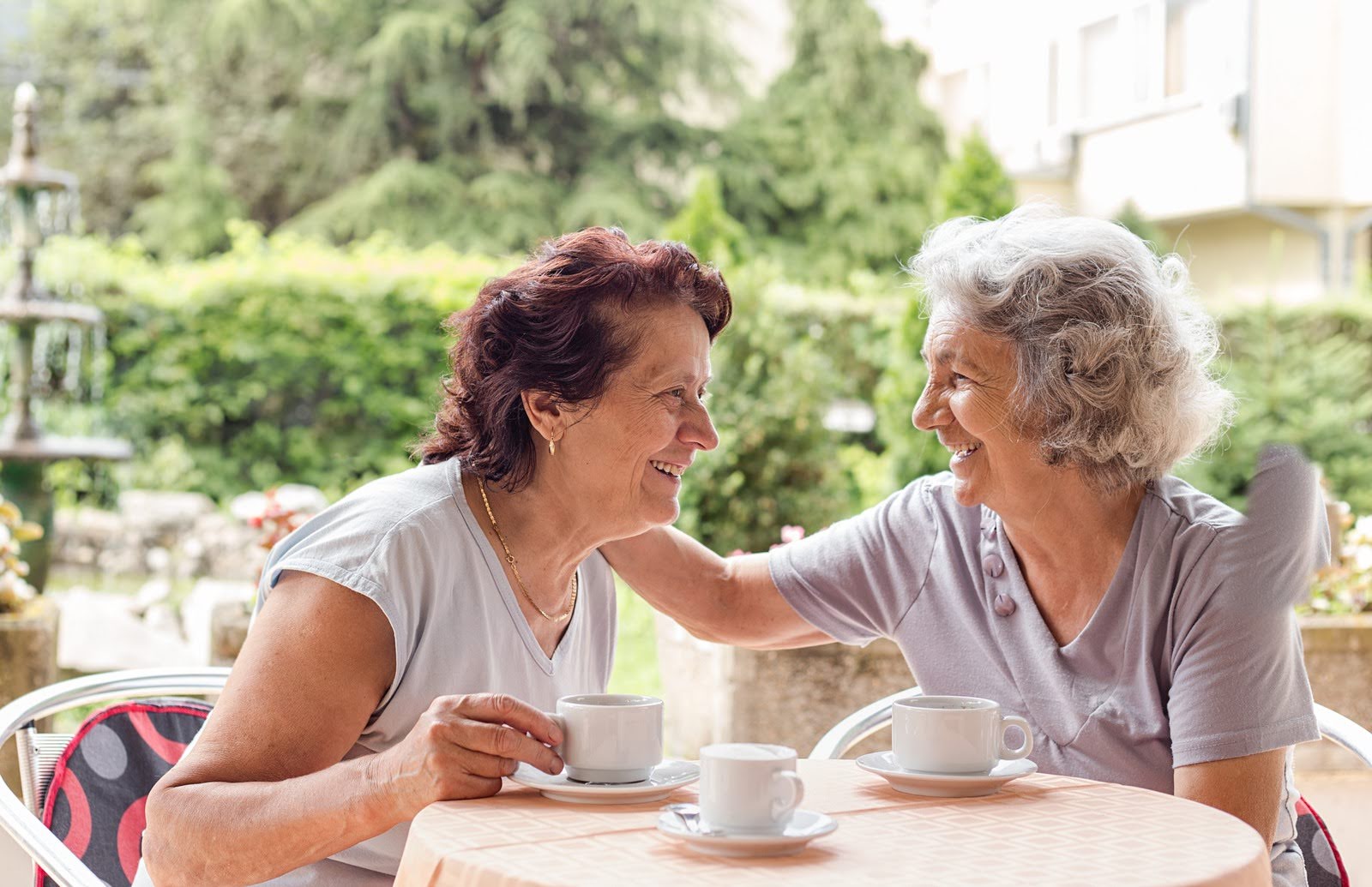 Two senior women friends drinking coffee, smiling, and having a lovely conversation